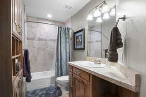 Upstairs hall bath with travertine shower and built-in cabinet organizer.