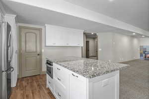 Basement/AUD kitchen featuring white cabinets, stainless steel appliances, wood look tile floors and granite countertops
