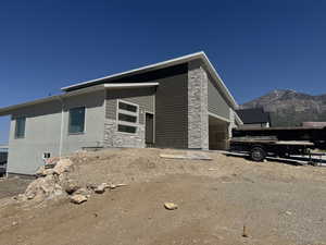 View of home's exterior featuring a mountain view, stone siding, and a garage