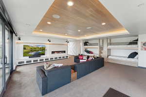 Carpeted living room with a raised ceiling, wood ceiling, and recessed lighting