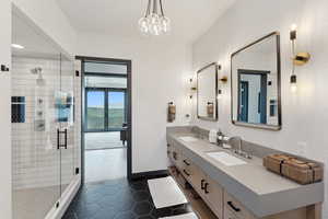 Bathroom featuring double vanity, a shower stall, baseboards, tile patterned flooring, and a chandelier