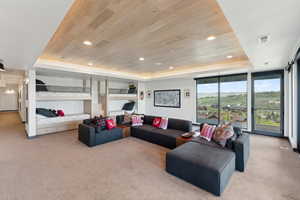 Living area with a tray ceiling, wood ceiling, light carpet, recessed lighting, and floor to ceiling windows