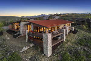 Rear view of property featuring stone siding, a deck with mountain view, and metal roof