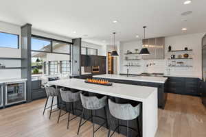 Kitchen with open shelves, a spacious island, light countertops, light wood-style flooring, and recessed lighting