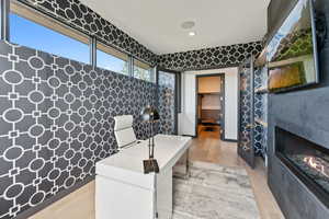 Home office with light wood-style floors, a glass covered fireplace, and recessed lighting