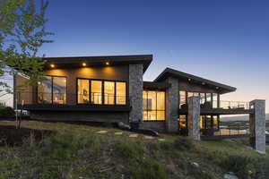 Back of property featuring stone siding and a balcony