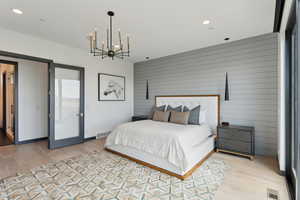 Bedroom with light wood-type flooring, a chandelier, wooden walls, recessed lighting, and baseboards
