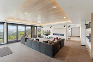Carpeted living area featuring a tray ceiling, recessed lighting, baseboards, and wood ceiling
