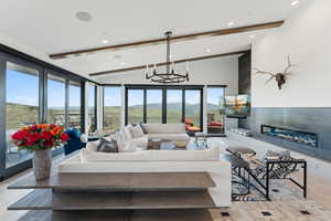 Living room featuring a glass covered fireplace, a chandelier, wood finished floors, and recessed lighting