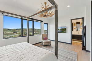 Bedroom featuring a chandelier, light wood finished floors, recessed lighting, baseboards, and connected bathroom