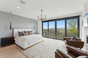 Bedroom with access to outside, a chandelier, light wood finished floors, recessed lighting, and wooden walls