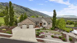 View of front facade with a garage, a mountain view, stone siding, and concrete driveway