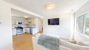 Living room with a textured ceiling, baseboards, and light wood-style floors