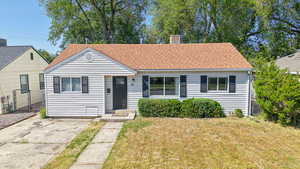 Bungalow-style home with a gate, roof with shingles, and a chimney