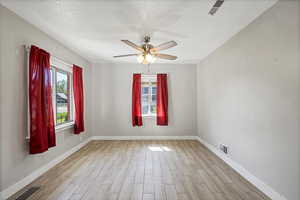 Unfurnished room with light wood-type flooring, a textured ceiling, baseboards, and ceiling fan