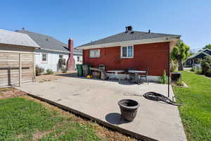 Rear view of house featuring a patio area, central AC unit, brick siding, and a shingled roof