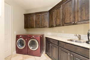 Laundry room featuring cabinet space, washing machine and dryer, and light tile patterned floors