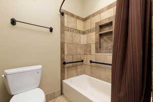 Bathroom with toilet and shower / bathtub combination with curtain
