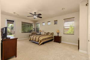 Bedroom with light colored carpet, multiple windows, baseboards, and a ceiling fan