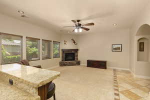 Living room with a stone fireplace, recessed lighting, baseboards, light tile patterned floors, and arched walkways