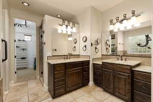 Full bathroom with two vanities, decorative backsplash, and a walk in closet