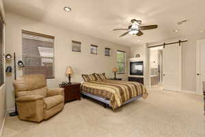 Bedroom featuring a barn door, carpet, recessed lighting, ensuite bath, and ceiling fan