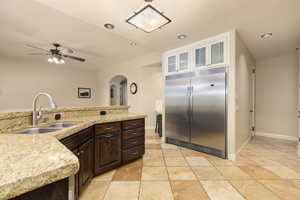 Kitchen with stainless steel built in fridge, arched walkways, a sink, a ceiling fan, and dark brown cabinets