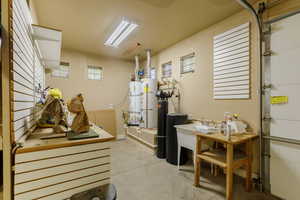 Garage with strapped water heater, a sink, and water heater