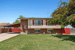 Tri-level home with an attached carport, brick siding, and driveway