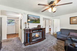 Living room with carpet, a ceiling fan, and baseboards
