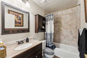 Full bathroom featuring vanity, toilet, and shower / bathtub combination with curtain