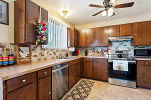 Kitchen featuring stainless steel appliances, a sink, under cabinet range hood, a textured ceiling, and a ceiling fan
