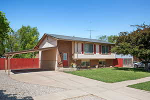 View of front of property featuring brick siding, concrete driveway, and a carport