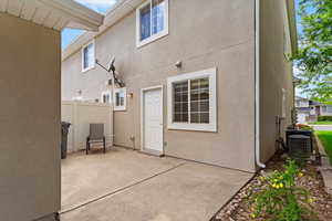Rear view of house with a patio area, cooling unit, and stucco siding