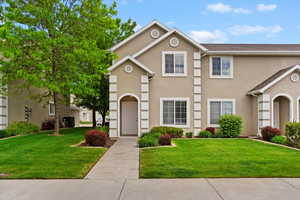 View of property with stucco siding and a front lawn