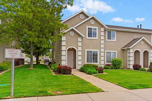 Multi unit property featuring stucco siding and a front lawn