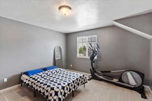 Carpeted bedroom with a textured ceiling and baseboards