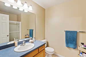 Bathroom with vanity, toilet, a shower stall, tile patterned floors, and baseboards