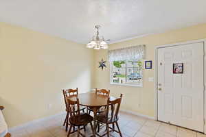 Dining room featuring a chandelier, light tile patterned floors, and baseboards
