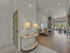 Living room with wood finished floors, a towering ceiling, recessed lighting, and a chandelier