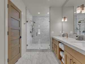 Bathroom with marble look tiles, a marble finish shower, recessed lighting, double vanity, and baseboards