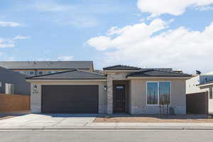 Prairie-style home with an attached garage, driveway, stucco siding, brick siding, and a tiled roof