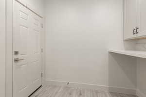 Doorway with baseboards and light wood-style flooring