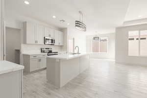 Kitchen with stainless steel appliances, a sink, recessed lighting, a kitchen island with sink, and pendant lighting