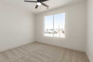Unfurnished room with light colored carpet, plenty of natural light, baseboards, and a ceiling fan