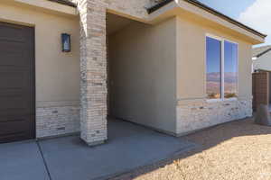 Property entrance with stucco siding, brick siding, and stone siding
