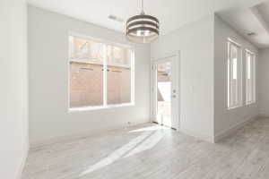 Unfurnished room featuring healthy amount of natural light, a chandelier, and wood tiled floors