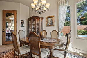 Dining room with a chandelier, light tile patterned floors, and baseboards
