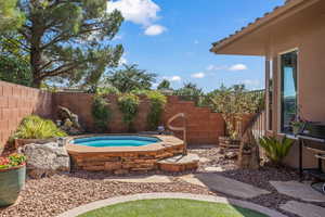 Fenced backyard featuring an in-ground hot tub