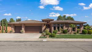 View of front of property featuring a garage, a tiled roof, stucco siding, and driveway